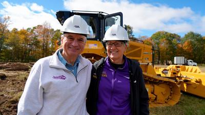 Alfred University administration smiling in front of a bulldozer